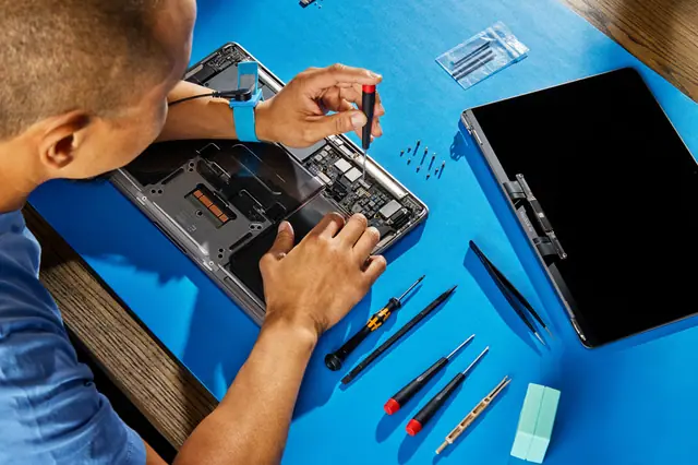 Technician repairing a MacBook on an anti-static mat